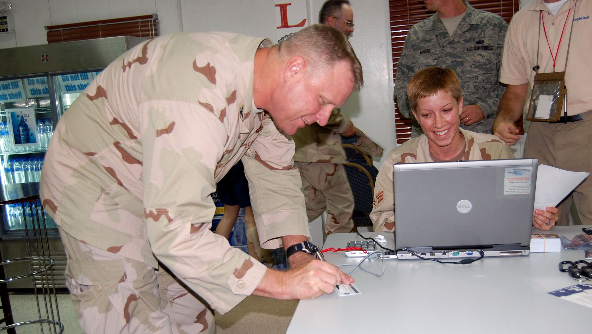 Col. Robert Swisher signs for his Eagle Cash card Sept. 11 at the Flex Recreation Center in Southwest Asia. Cardholders can use Eagle Cash cards even when local ATMs are down or if the base exchange credit or debit lines are down. Colonel Swisher is the 386th Air Expeditionary Wing commander. (U.S. Air Force photo/Staff Sgt. Phillip Butterfield)