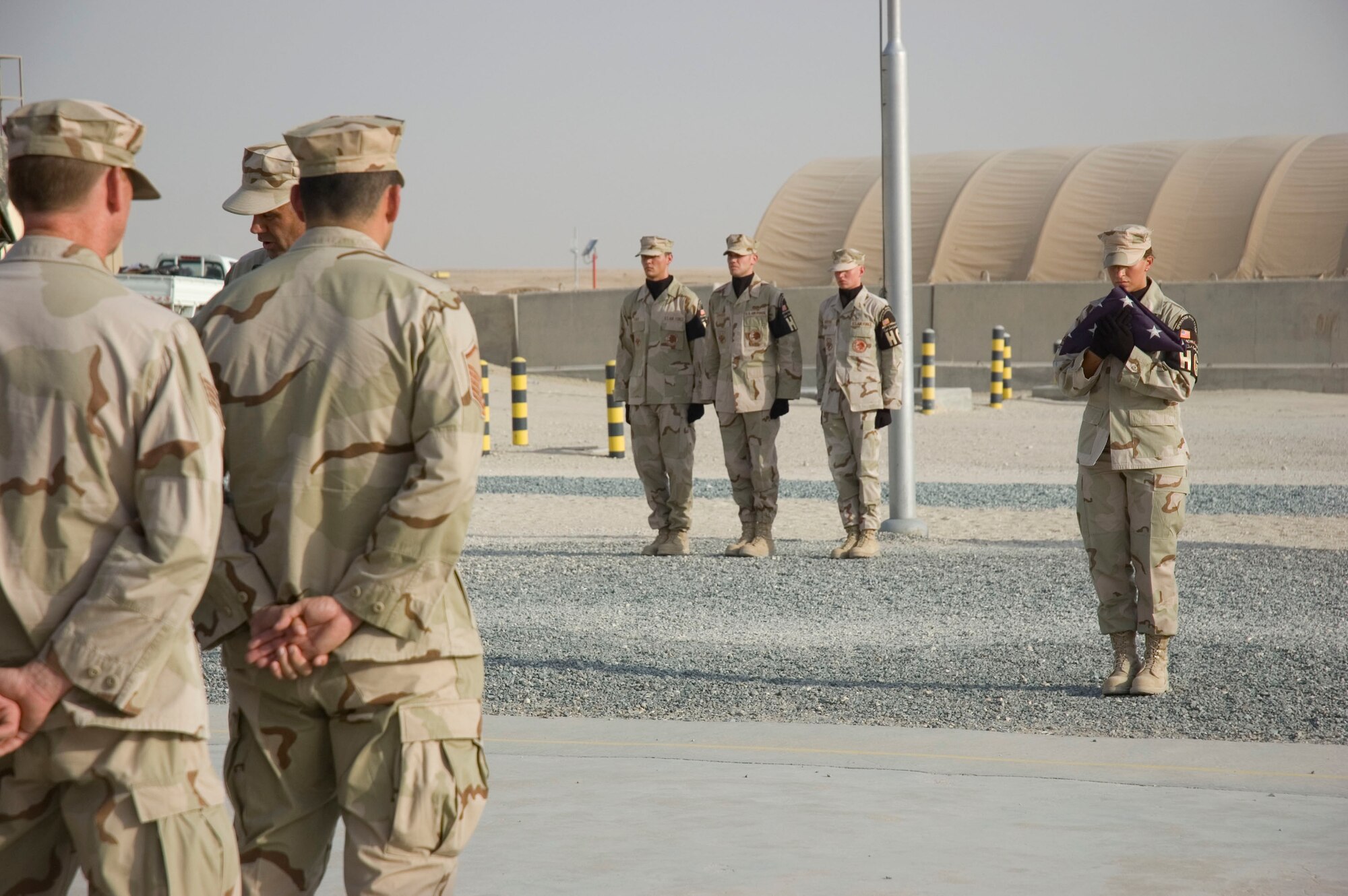 Honor Guardsmen Staff Sergeant Heather Wright prepares to present the flag to Senior Master Sgt. Edward Metcalf during a tribute to the men and women who lost their lives during the Sept. 11, 2001, remembrance ceremony Sept. 11 at an undisclosed location in S.W. Asia. The ceremony marked the sixth anniversary of the terrorist attacks in New York City, the Pentagon and Shanksville, Pa. (U.S. Air Force photo illustration by SSgt Tia Schroeder)