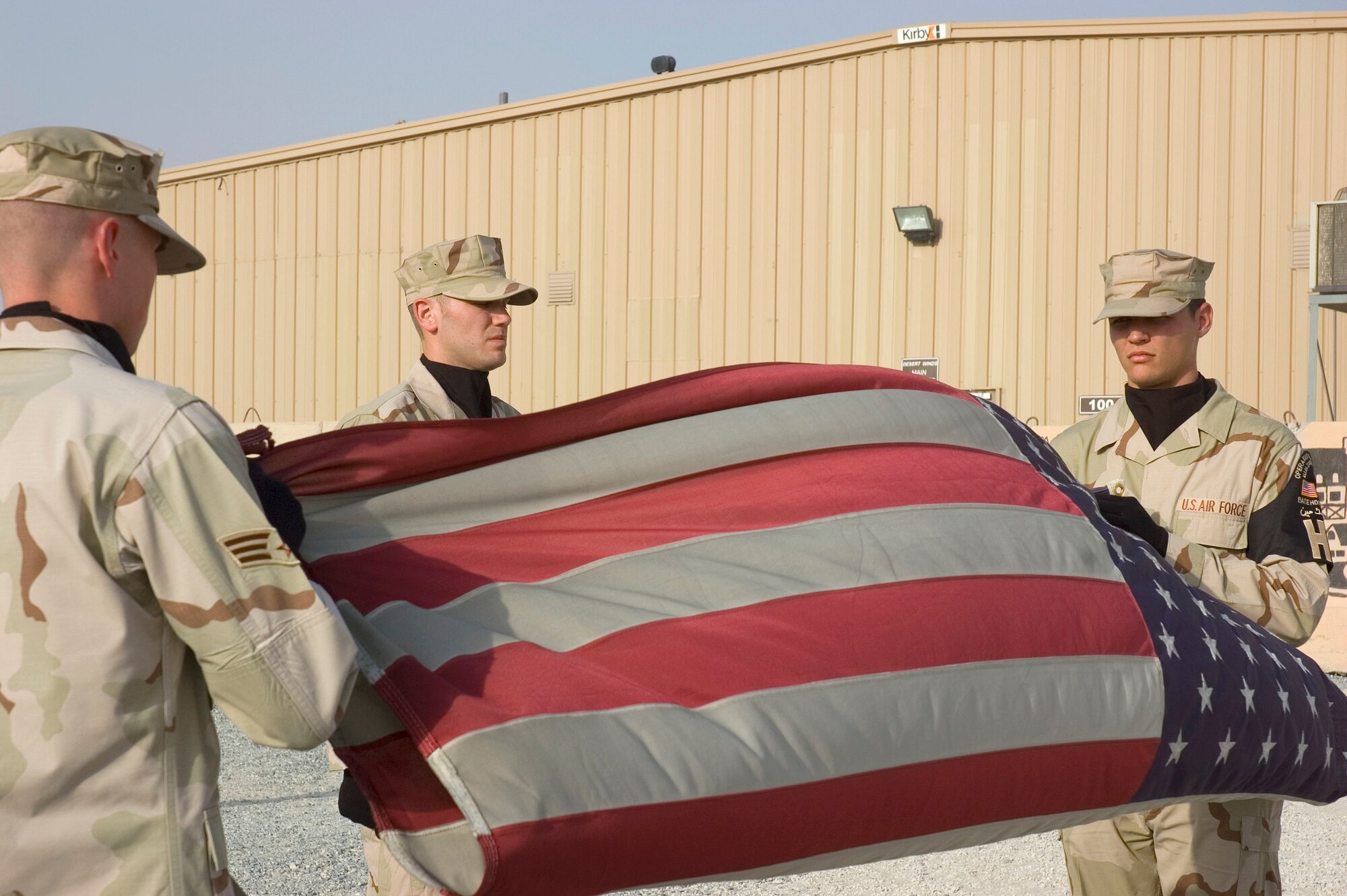 (L to R) Senior Airman Blaine Andrews, Staff Sgt. Brian Johnson, and Senior Airman Roger Lyday from the 386th Air Expeditionary Wing Honor Guard perform a flag folding detail to pay tribute to the men and women who lost their lives during the Sept. 11, 2001, remembrance ceremony Sept. 11 at an undisclosed location in S.W. Asia. The ceremony marked the sixth anniversary of the terrorist attacks in New York City, the Pentagon and Shanksville, Pa. (U.S. Air Force photo illustration by SSgt Tia Schroeder)