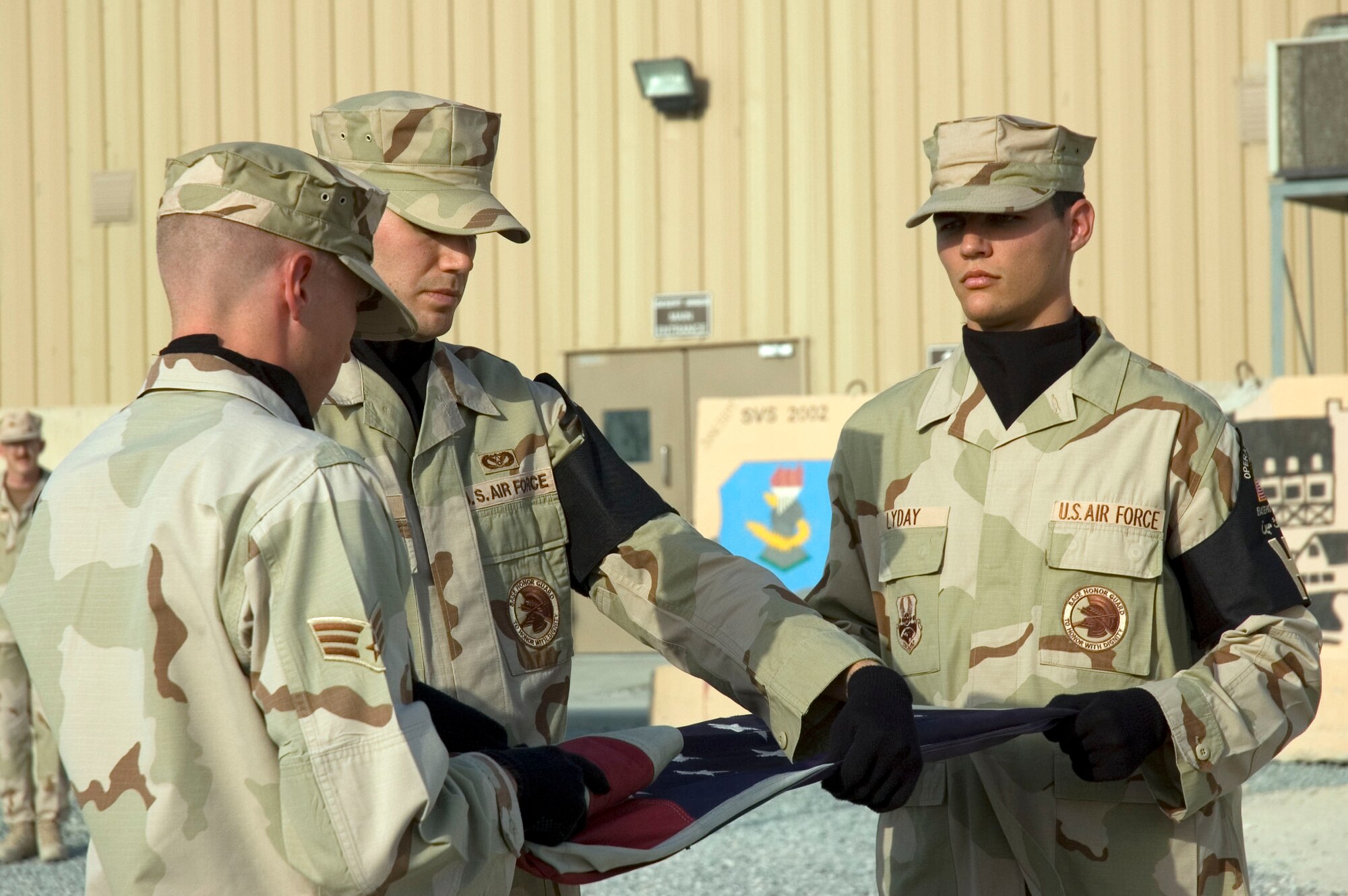 (L to R) Senior Airman Blaine Andrews, Staff Sgt. Brian Johnson, and Senior Airman Roger Lyday from the 386th Air Expeditionary Wing Honor Guard perform a flag folding detail to pay tribute to the men and women who lost their lives during the Sept. 11, 2001, remembrance ceremony Sept. 11 at an undisclosed location in S.W. Asia. The ceremony marked the sixth anniversary of the terrorist attacks in New York City, the Pentagon and Shanksville, Pa. (U.S. Air Force photo illustration by SSgt Tia Schroeder)