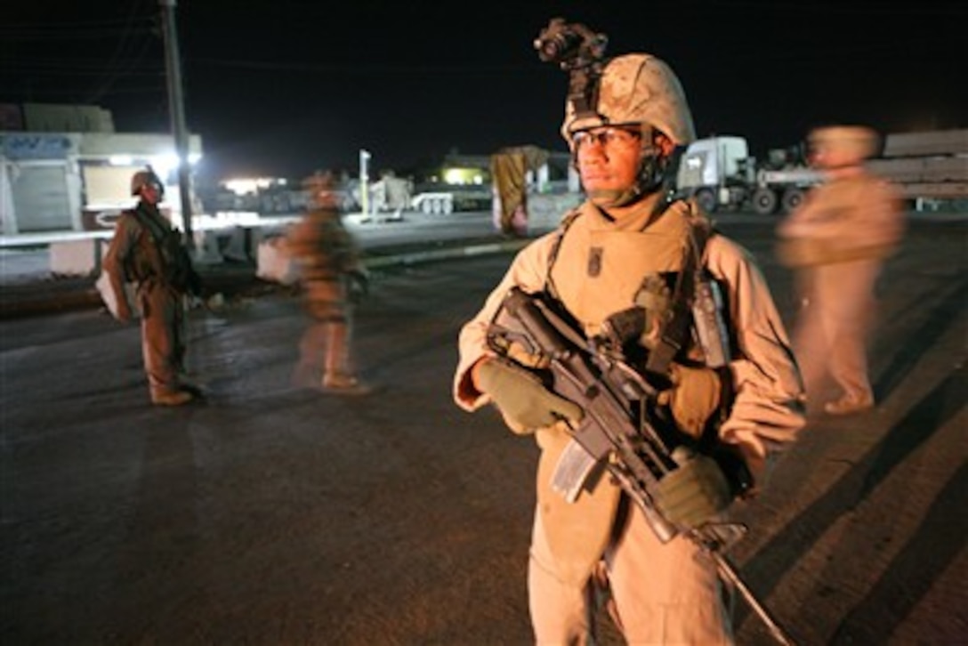 A U.S. Marine with Echo Company, 2nd Battalion, 6th Marine Regiment provides security for fellow Marines as they use a forklift to place concrete barriers along roads in Fallujah, Iraq, on Sept. 4, 2007.  Marines with the Combat Engineer Battalion are placing the barriers to assist in controlling the flow of vehicle traffic.  