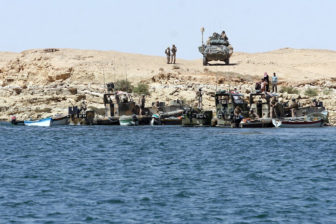 HADITHA DAM, Iraq, (Sept. 16, 2007) – A light armored vehicle with Light Armored Reconnaissance Battalion, Regimental Combat Team 2, provides over watch for boats with Detachment 3, Riverine Squadron 1, Riverine Group 1,  Navy Expeditionary Combat Command. The sailors searched several civilian fishing boats and conducted sweeps of the Euphrates River in support of the regiment and 1st LAR. The squadron is the first Navy riverine unit to be forward deployed by the Navy since the Vietnam War. Official Marine Corps Photo By Cpl. Ryan C. Heiser.