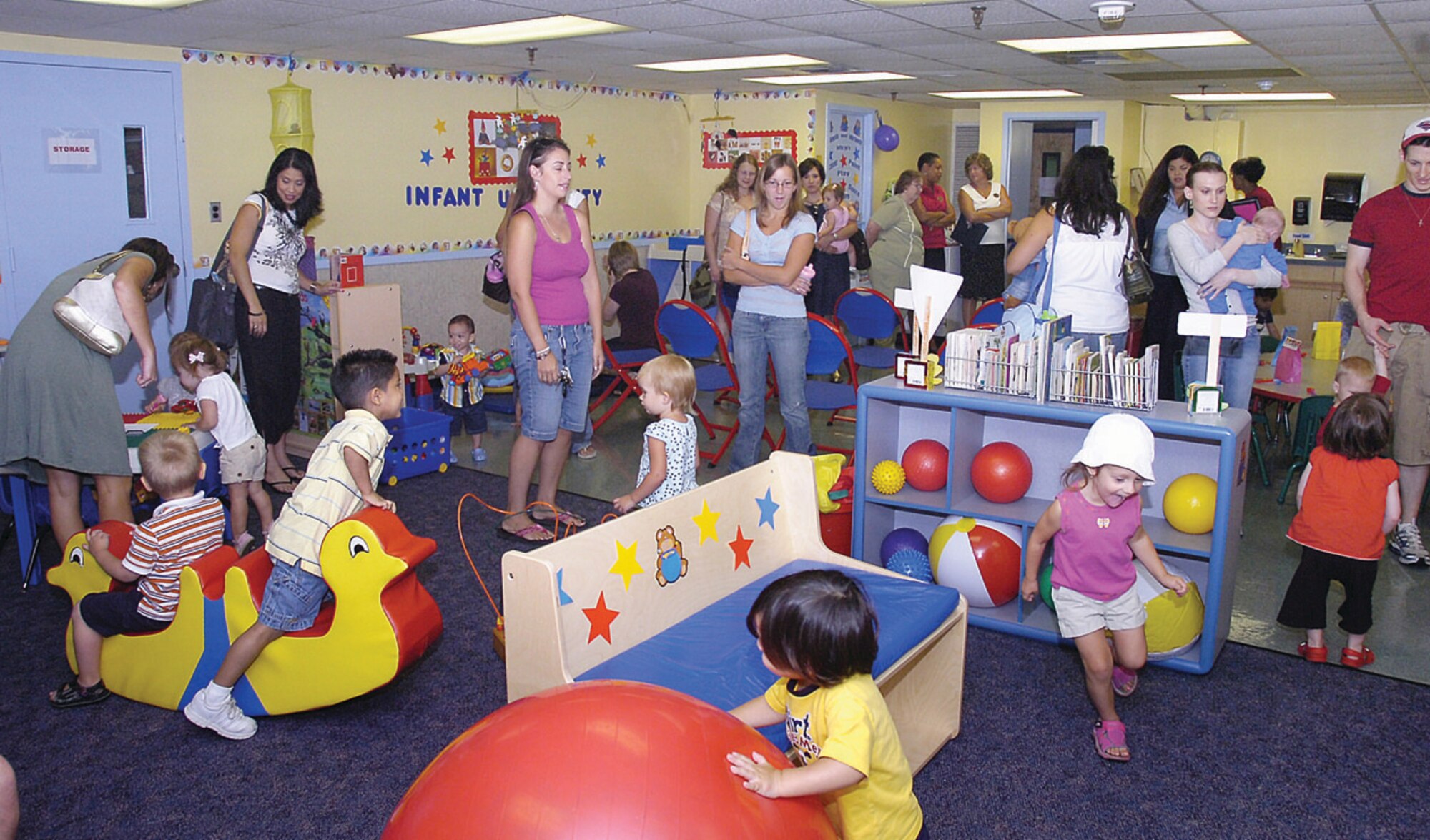 Several parents mingle in the new facility as their children played in the new Infant and Toddler University multipurpose playroom provided by Child Development Center 1 Aug. 28. (US Air Force/Bobby Jones)