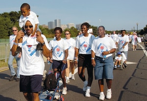 Tech. Sgt. Stephen Parker, left, carries his son, Khalon, 3, as his wife, Tech. Sgt. Kenyel Parker, center, Harriet Pullian and Tech. Sgt. Dawniel Conner particpate in the third annual Freedom Walk from the Lincoln Memorial to the Pentagon last Sunday. Approximately ten thousand civilian and military participants walked in support of the men and women who died September 11, 2001.