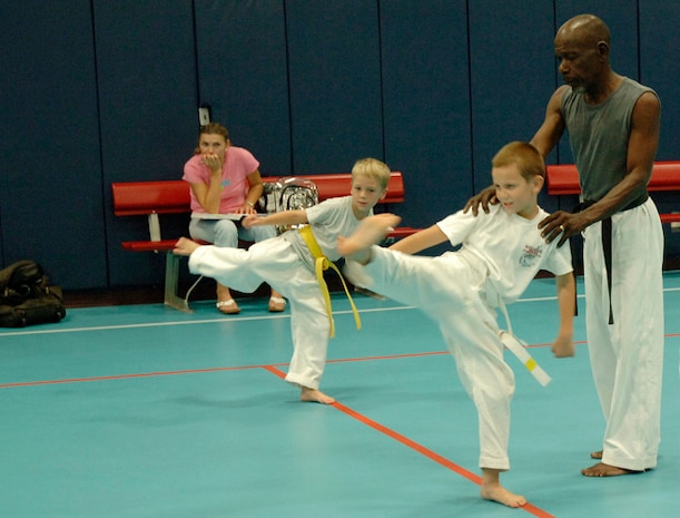 Instructor Mitch Jenkins assists David Turasov, 7, and Riley Newsom, 8, son of Master Sgt. Kevin Newsom,with their kicking excerises during Tae Kwon Do practice as David's mother, Mariya Gillum, watches them at the Youth Programs Center on base Wednesday.  (U.S. Air Force photo/Staff Sgt. April Quintanilla)