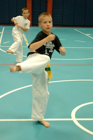 Brandon Pugh, 9, son of Master Sgt. Shawn Pugh, and David Turasov, 7, son of Tech. Sgt. Randall Gillum, do kicking exercises to warm up for Tae Kwon Do class at the base Youth Programs Center Wednesday. (U.S. Air Force photo/Staff Sgt. April Quintanilla)