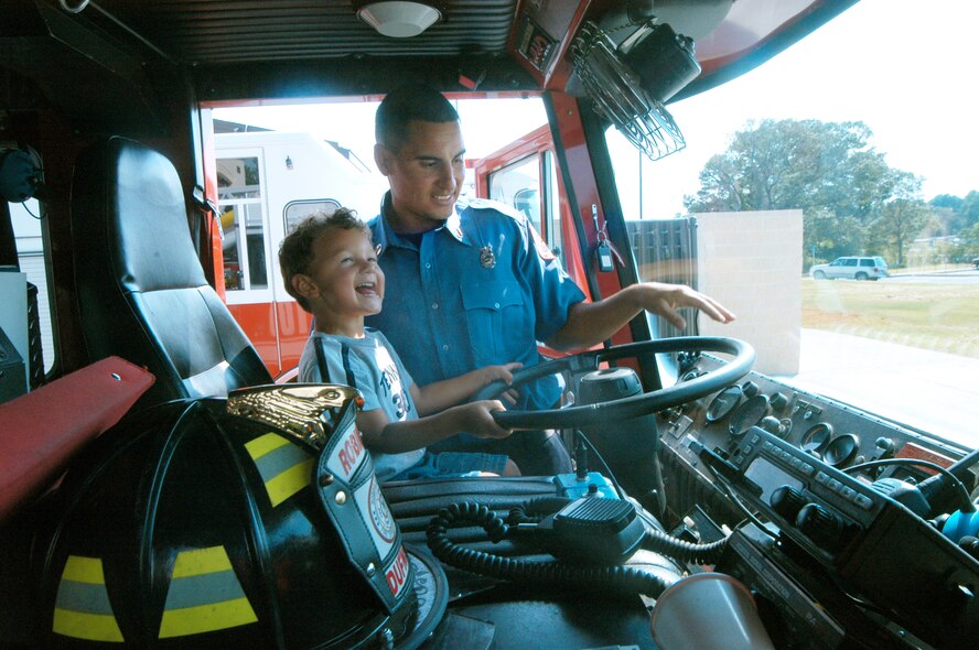 Engineer Javie Blanco shows his son Jessdon, 3, the driver's seat of Engine 10, the firetruck he drives at the opening of the new fire station at Robins Tuesday. U. S. Air Force photo by Sue Sapp 