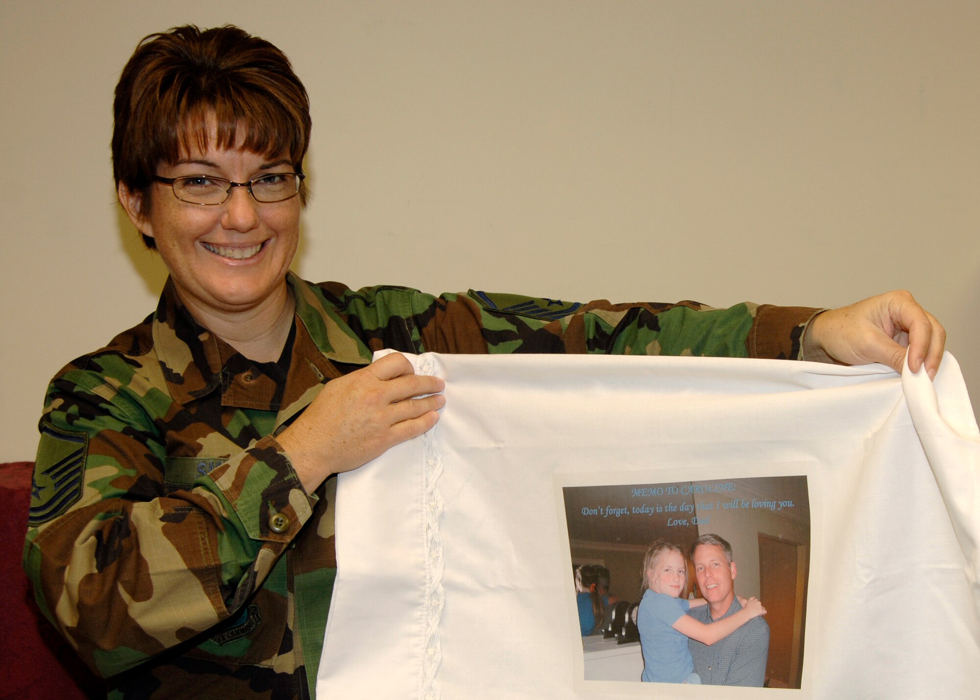 Master Sgt. Susan Smith, 22nd Mission Support Squadron, holds up a finished, etched pillow case Aug 29.  Operation Rest is a program at the McConnell Airmen and Family Readiness Center allowing family members of deployed Airmen to either bring in photos or send photos through e-mail to the AFRC so the images can be pressed onto a pillowcase or T-shirt along with a personal message. (Photo by Airman 1st Class Laura Suttles)