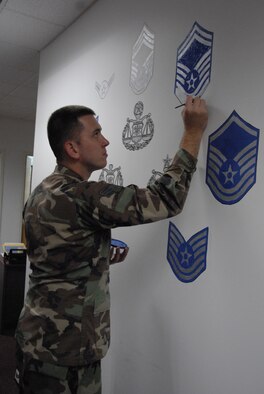 Hanscom Air Force Base, Mass. -- Senior Airman Timothy Galloway, 66th Air Base Wing Judge Advocate Office, adds the finishing touches to a beautification project in the lobby of the Legal Office Sept. 10. 
“So many people automatically think of attorney or ‘JAG’ when they hear the words ‘legal office,’” Airman Galloway said. “[The Legal Office] wanted to pay tribute to the hard working and knowledgeable enlisted paralegals, those before us and for those after, which dedicate their time and service to the Air Force Legal mission.
“I want it to just represent the type of dedication that we have and I want others to see what we are capable of when given a task,” he said. (U.S. Air Force photo by Senior Airman Clinton Atkins)
