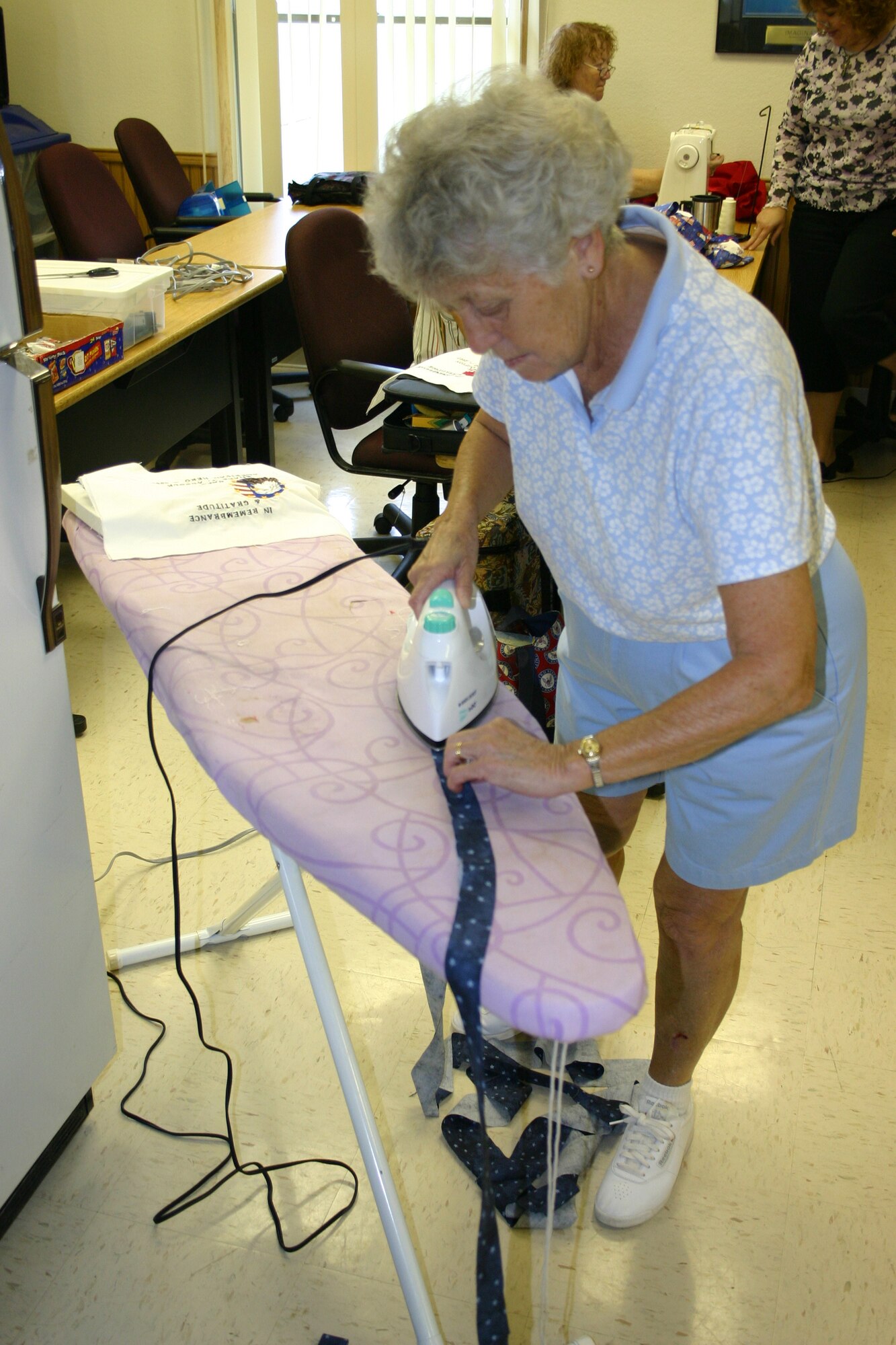 Mary Barlow irons a strip of cloth during a meeting of Operation Homefront Quilts. The national group makes quilts for the family members of deceased servicemembers. Mrs. Barlow is the mother of Col. Babette Lenfant, 27th Mission Support Group commander. (U.S. Air Force photo by Airman Elliott Sprehe)