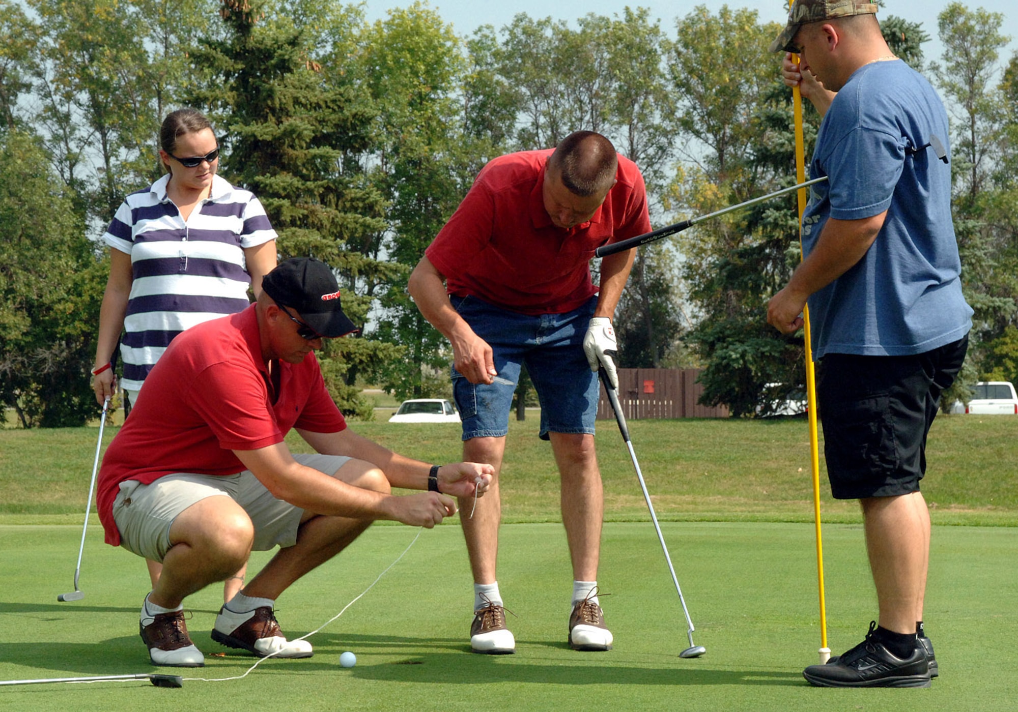 Maj. Rick Hughes, 319th Logistics Readiness Squadron, measures the distance of the golf ball piont of stance to the hole as the other team members look on for approval. Wing leaders used putters and drivers to support Airmen Against Drunk Driving during the AADD golf tournament Sept. 5 at a local golf course. AADD supports the wing?s mission of creating a culture of responsible drinking by maintaining a staff of on-call volunteers who are available to give rides home to Airmen (U.S. Air Force photo/Senior Airman SerMae Lampkin)