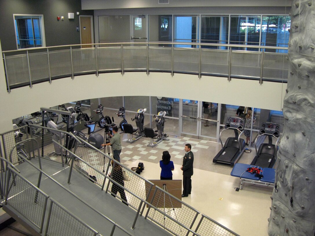 An indoor running track encircles the “upper-extremities” workout areas of the new Military Advanced Training Center at Walter Reed Army Medical Center. One half of the top floor is open, allowing soldiers to look down on others using “lower–extremities” workout equipment. A climbing wall rises from the lower level, and climbing ropes and a rappelling wall allow patients to develop overhead skills and confidence. Windows allow sunlight to stream throughout. Photo by Fred W. Baker III