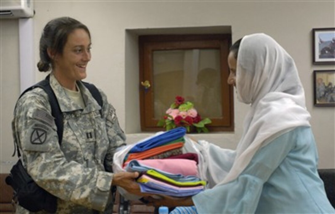 U.S. Air Force Capt. Christa Lothes hands donated materials for a sewing class to a local Afghan woman during an afternoon tea at Forward Operating Base Mehtar Lam, Afghanistan, on Sept. 5, 2007.  Female airmen and soldiers assigned to the Laghman Provincial Reconstruction Team hosted the tea for Afghan women living throughout Afghanistan's Laghman province.  