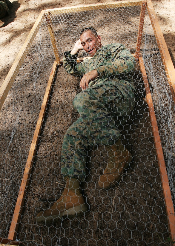 MARINE CORPS BASE, CAMP H.M. SMITH, Hawaii --  Sgt. Julio Sandoval lays in a simulated tiger cage during a period of military education about the prisoners of war during the vietnam war era here Sept. 14. The cage he layed in was more than a foot wider and longer than the real cages used by the North Vietnamese to torture POWs.  (Official USMC Photo by Cpl. R. Drew Hendricks)