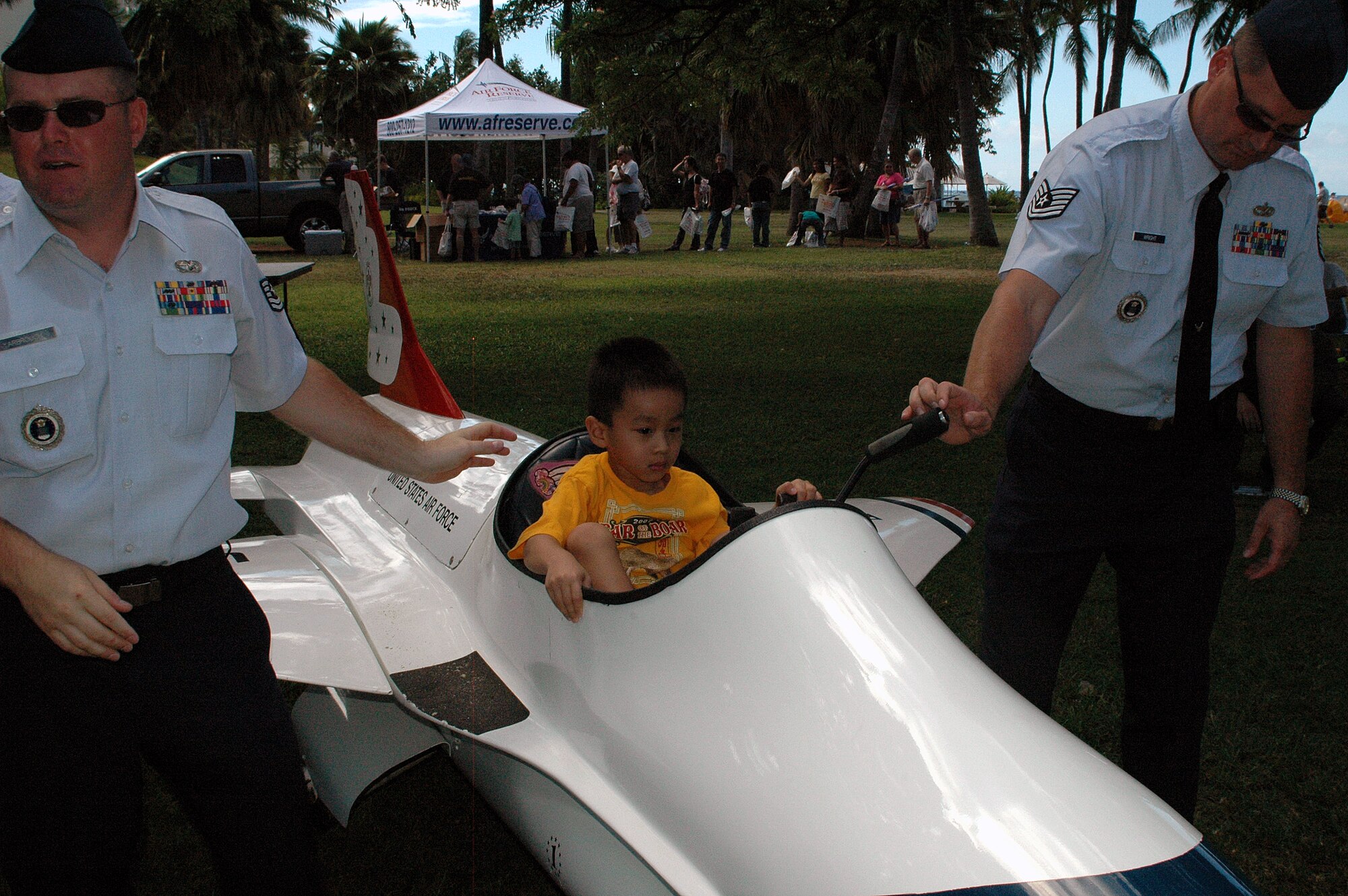 FORT DERUSSY, Hawaii -- Jordan Lee, 5, tests out the controls of one of the two F-16 Thunderbird mini jets while Tech. Sgt. Chris Yarbrough (left), recruiter from the Big Island, and Tech. Sgt. Larry Wright, Headquarters Air Force Recruiting, assist as wingmen at Fort DeRussy Sept. 13. The recruiters also had an F-22 mini jet and gave the children rides around the park. (U.S. Air Force photo by Tech. Sgt. Bryan Gatewood)