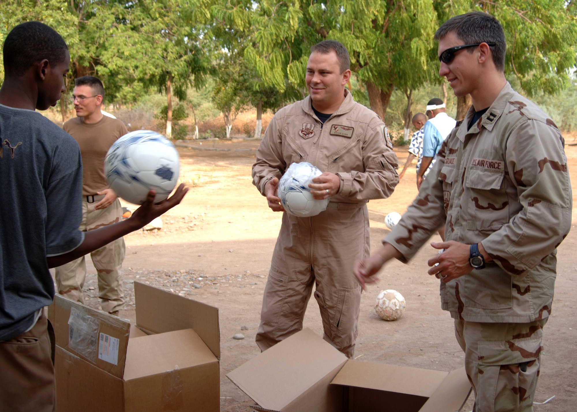 Maj. Bryan Dunn (center) and Capt. Andy McQuade hand out soccer balls to boys at a local orphanage in Djibouti. More than 80 soccer balls were donated from soccer clubs in Georgia and Colorado and from several colleges across the United States. Major Dunn and Captain McQuade are assigned to the Combined Joint Task Force-Horn of Africa.  (U.S. Navy photo/Petty Officer 2nd Class Regina L. Brown)