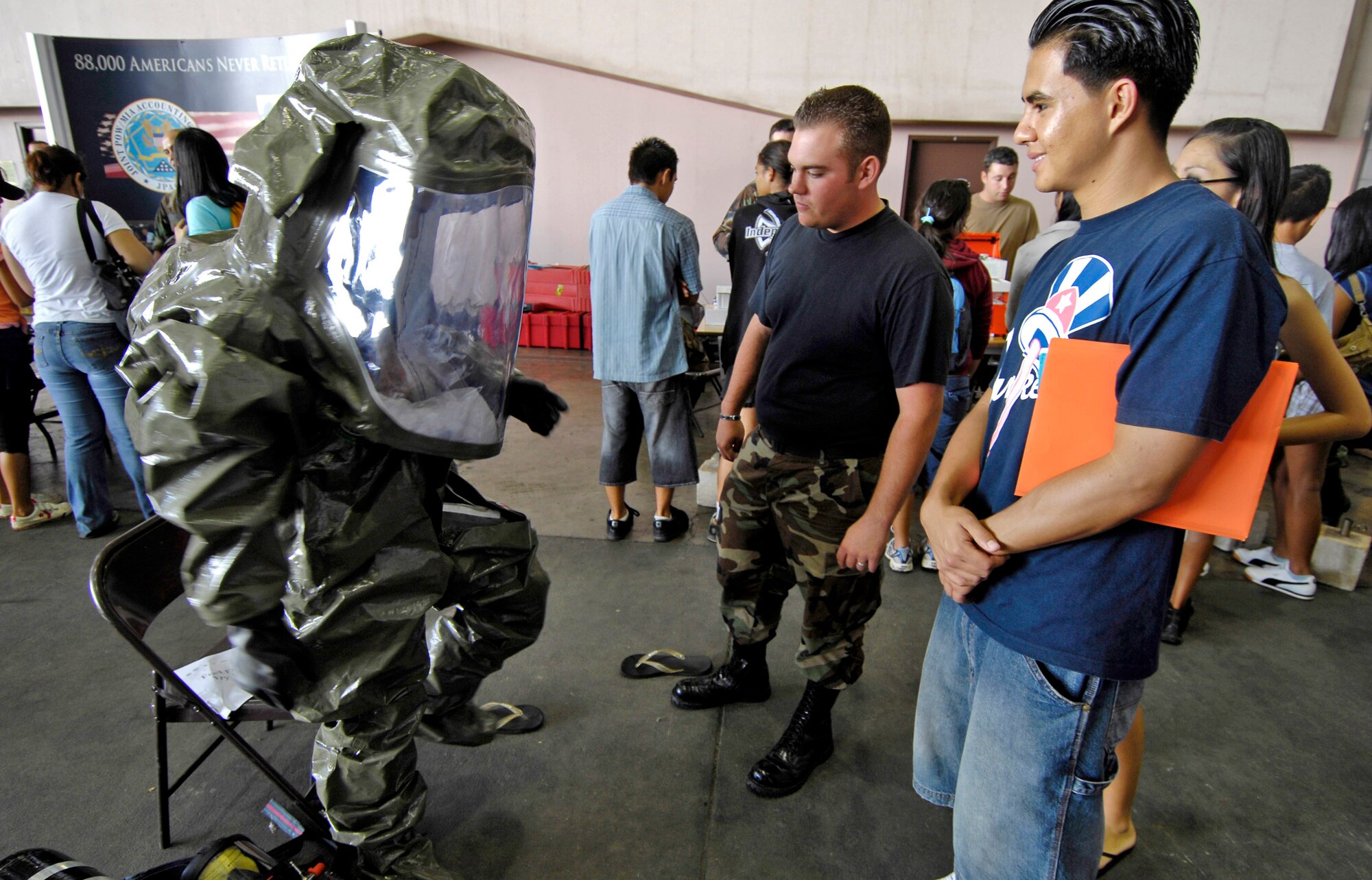 Airman 1st Class Tim Batley watches as a high school student tries on a protective suit Sept. 13 at Hickam Air Force Base, Hawaii, during Air Force Education Day. Members of 13th Air Force hosted the day for Hawaii public school math and science students as part of Air Force Week Honolulu. Airman Batley is a bioenvironmental engineer from Hickam. (U.S. Air Force photo/Tech. Sgt. Shane A. Cuomo) 