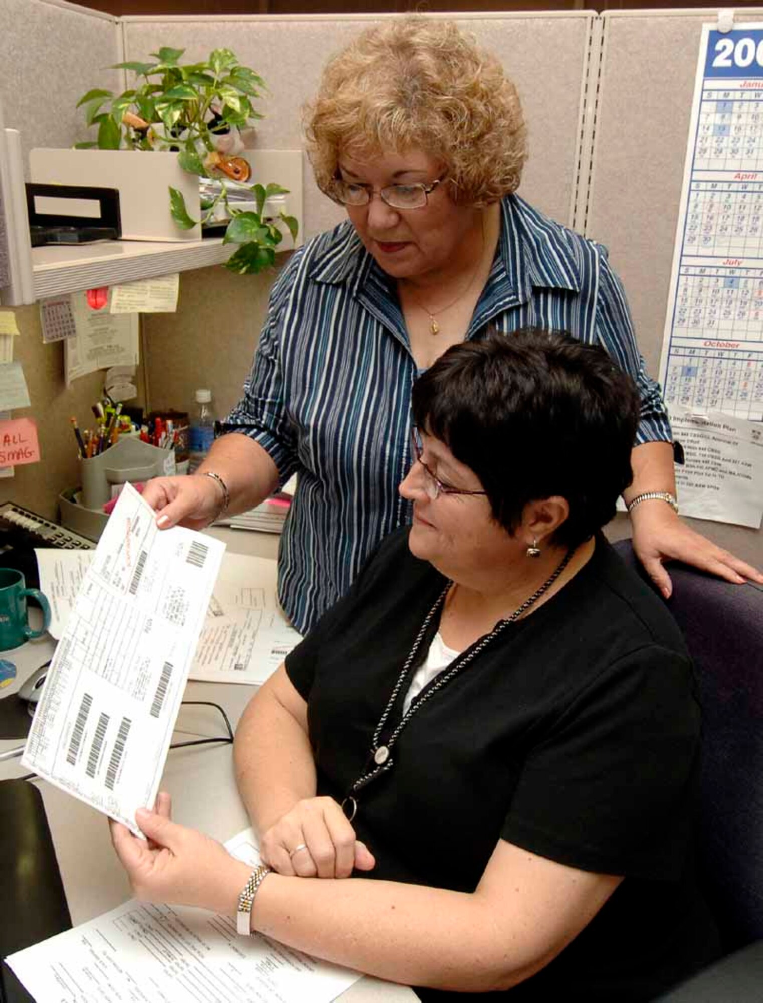 Donna Nick, editing specialist, and Janie Ramon, TO writer/editor check a computer-printed label to ensure the proper number of documents will be shipped and to the right customer under the Print-on-Demand initiative. (Air Force photo by Kirk McPheeters)