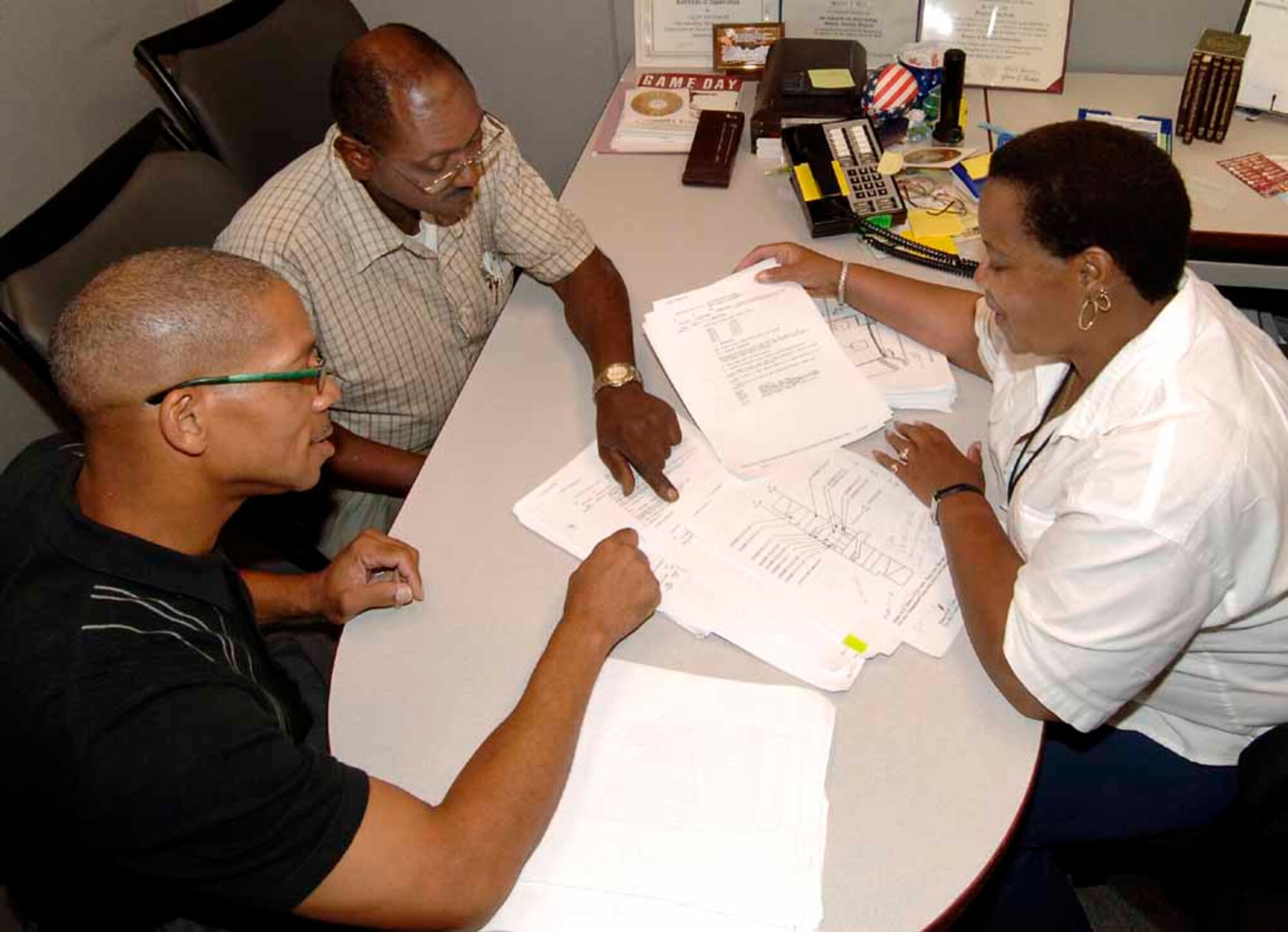 From left: TO Manager Cornelious Barnett, TO Equipment Specialist Ira Hodge, and TO Writer/Editor Sylvia Buckner meet to review a modified TO and ensure all requested changes were incorporated into the new document. (Air Force photo by Kirk McPheeters)