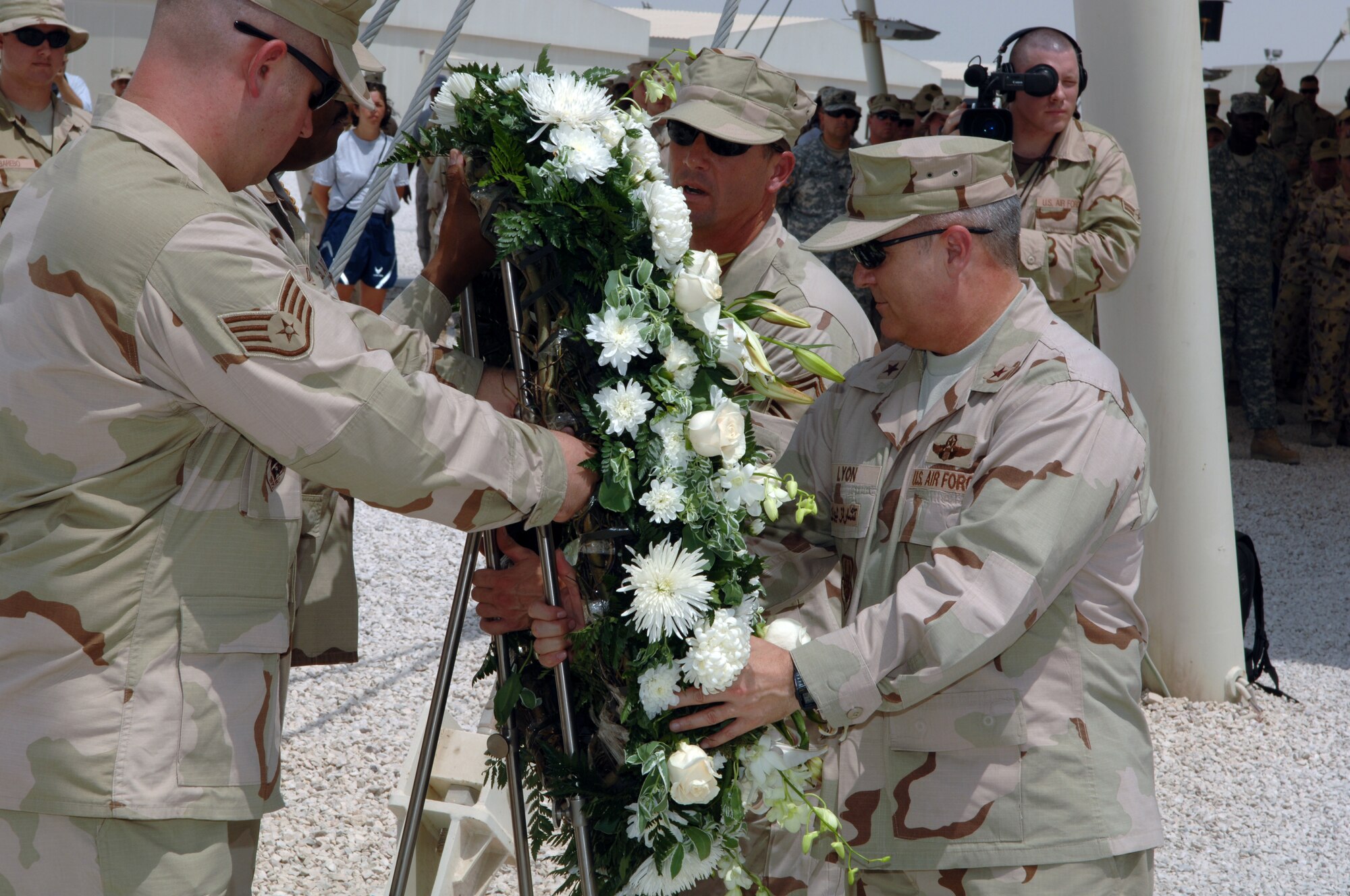 Staff Sergeant Jacob Ballard (left) assists Senior Master Sergeant Dale Hankins (center), 379th Air Expeditionary Wing Civil Engineer Squadron fire chief, and Brigadier General Charles Lyon, 379th Air Expeditionary Wing commander, in placing a memorial wreath before a flag pole to honor the victims of the 9-11 terrorist attacks.  Deployed members of the U. S. Armed Forces and its coalition allies took time to perform a memorial service in Southwest Asia on September 11, 2007.  (U.S. Air Force Photo/MSgt Ken Stephens) 