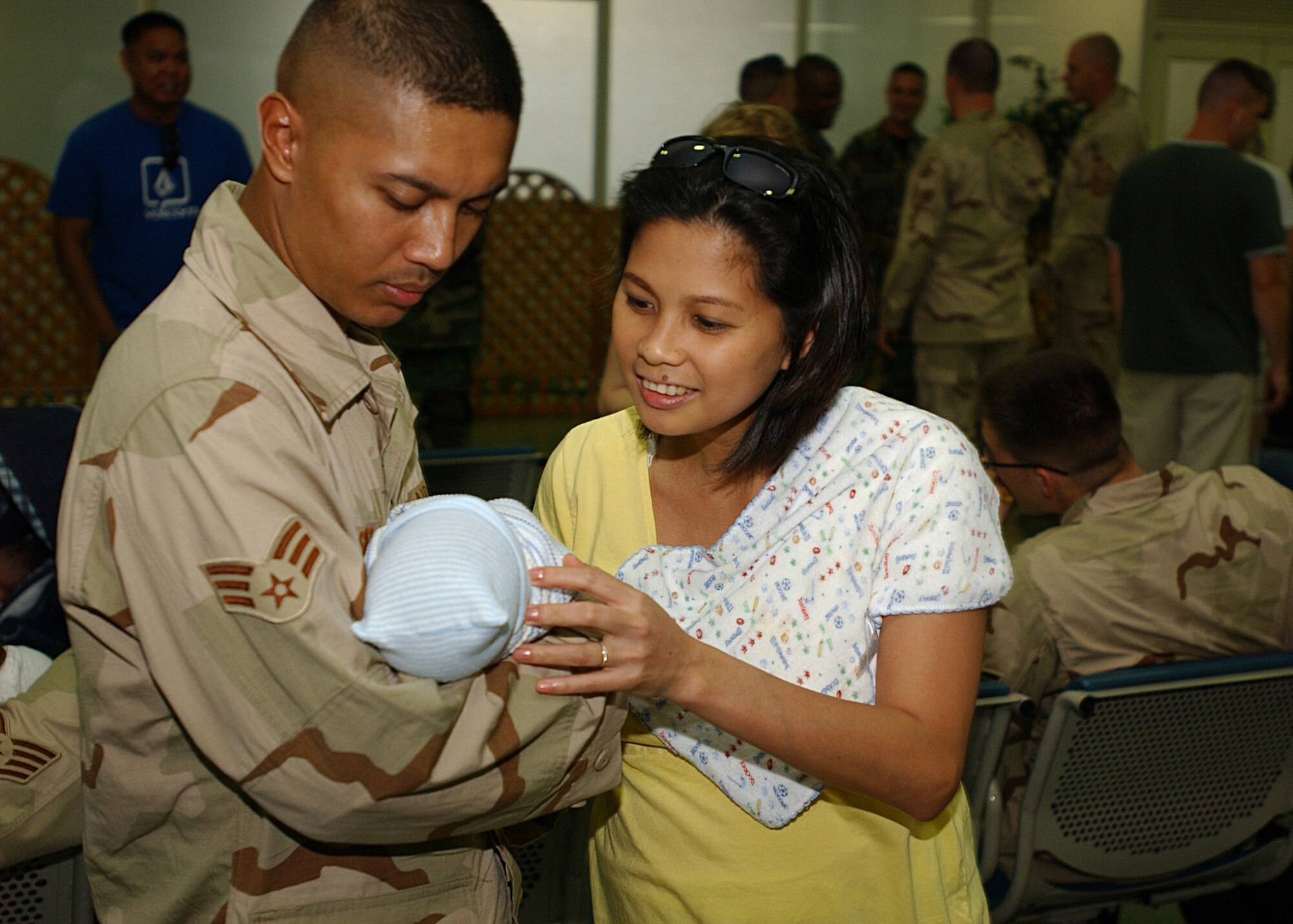 YOKOTA AIR BASE, Japan - Senior Airman Donald Sicat, from the 374th Civil Engineer Squadron, and his wife BenniFe Sicat hold their baby while waiting for SrA Sicat to leave for his deployment on September 15, 2007.  SrA Sicat is one of approximately 75 Airmen to depart and is part of the second group of Airmen to deploy during the current Air Expeditionary Force rotation. (U.S. Air Force photo by Airman First Class Jonathan Fowler)