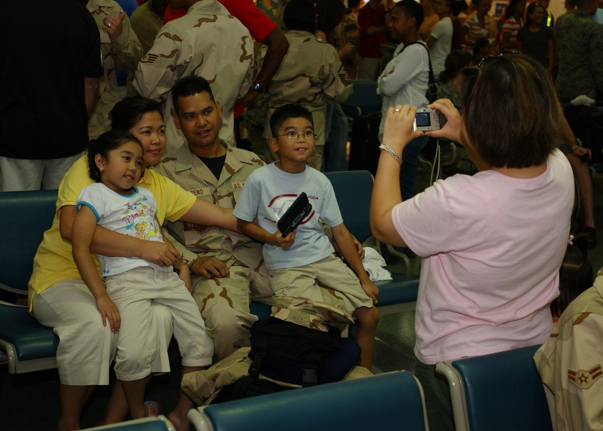 YOKOTA AIR BASE, Japan - Technical Sergeant Andre Empeno, from the 374th Logistics Readiness Squadron, takes a photo with his family while waiting to leave for his deployment on September 15, 2007.  TSgt Empeno is one of approximately 75 Airmen to depart and is part of the second group of Airmen to deploy during the current Air Expeditionary Force rotation. (U.S. Air Force photo by Airman First Class Jonathan Fowler)