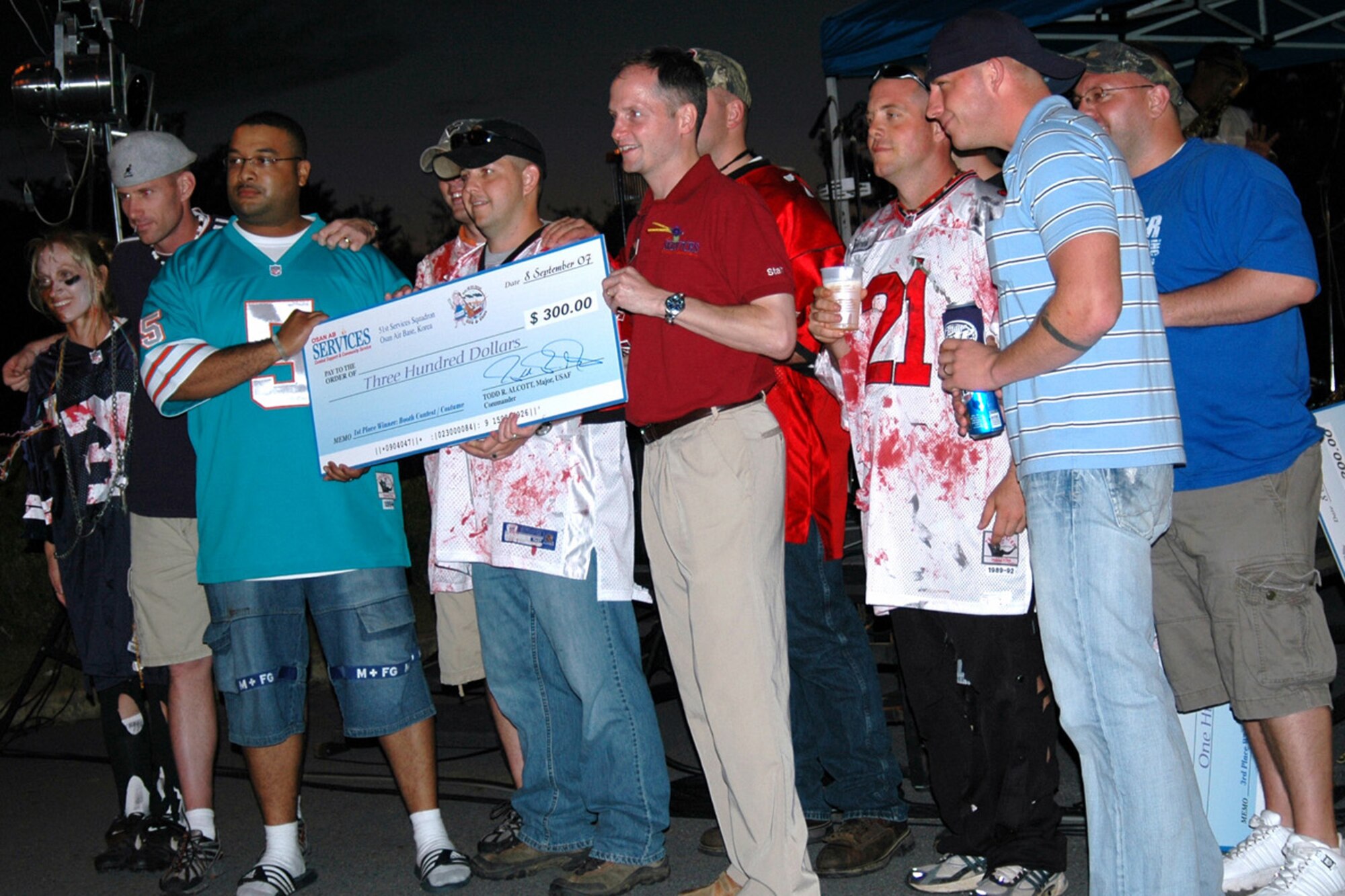 OSAN AIR BASE, Republic of Korea -- The members of "Bad Newz Kennels" accept their $300 check for winning the "Best Booth" contest at the Osan Barbecue and Blues Sep. 10.  The sixth annual Barbecue and Blues is sponsored by the 51st Services Squadron.  (U.S. Air Force photo by Master Sgt. Steven Goetsch)