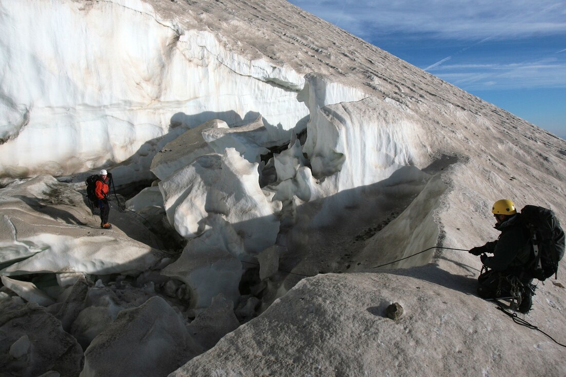 Inside a gaping crevasse at 9,500 feet, Tech Sgt. Anthony Reich, pararescueman, 304th Rescue Squadron, Portland, Ore., carefully makes his way around a couple of large ice blocks that have peeled off a melting glacier on Mount Hood, Ore. September 8.  Belaying Sergeant Reich with a safety rope is Staff Sgt. Patrick Dunne, pararescueman, 308th Rescue Squadron, Patrick Air Force Base, Fla.  The two were part of big weekend search for the bodies of two mountain climbers presumed killed during a firece December snowstorm.  An additional four pararescuemen from the 304th RQS and one SERE (search evasion resistance and escape) specialist from the 943rd Rescue Group, Tuscon, Ariz., joined Sergeants Reich and Dunne on the mountain.  In all their were 59 climbers, most of them volunteers from civilian moutain groups searching the high country.