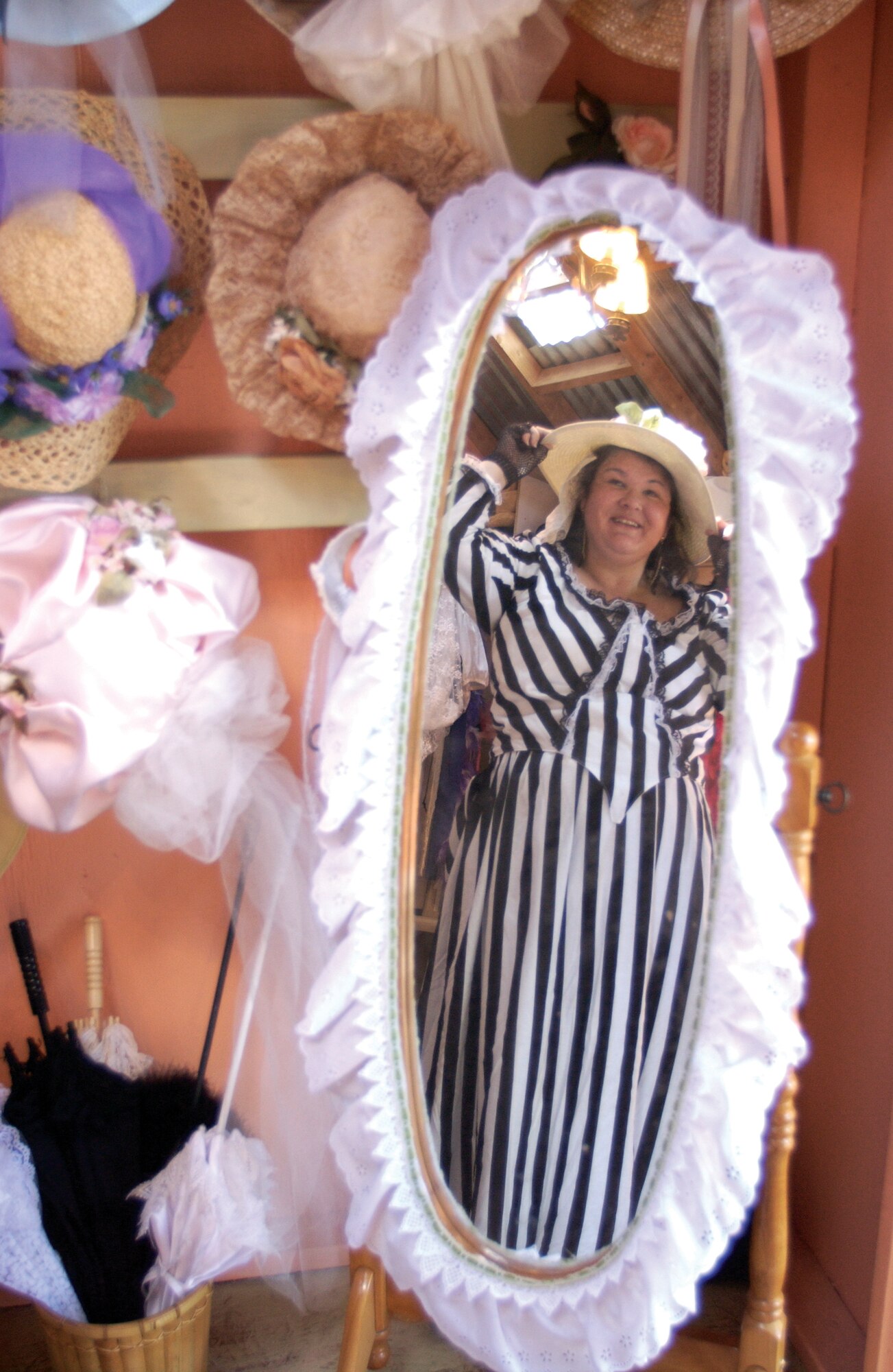 Jodelle Higginson, wife of Senior Master Sgt. Roughsedge "Skip" Higginson, tries on bonnets in the dressing room of their photo studio. The studio offers old western clothing and themed backdrops.  (U.S. Air Force photo by Amy Abbott)