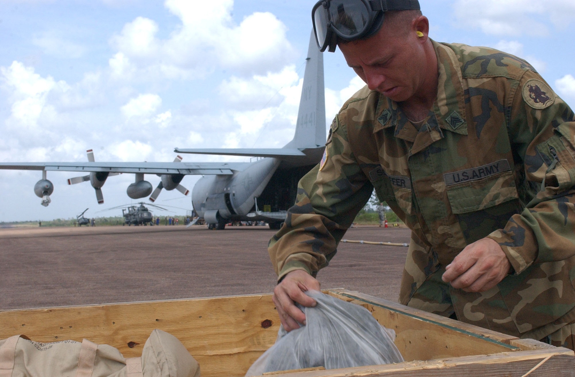 PUERTO CABEZAS, Nicaragua – Army Sgt. Robert Schaffer, 1st Battalion, 228th Aviation Regiment at Soto Cano Air Base, Honduras, retrieves supplies from a bin near a U.S. Marine Corps KC-130 assigned to the Marine Aerial Refueler Transport Squadron 452 (VMGR-452) here Sept. 15.  Sergeant Schaffer assisted with the setup of an Advanced Aviation Forward Area Refueling System to refuel aircraft supporting relief missions following Hurricane Felix. (U.S. Air Force photo by Tech. Sgt. Sonny Cohrs)