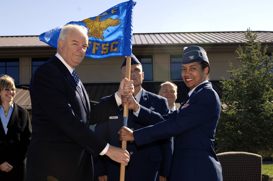 Secretary of the Air Force Michael Wynne hands the Air Force Financial Services Center guidon to Col. Judy Perry, AFFSC commander, during her assumption of command ceremony Sept 14. The center officially opened its door s to customers Sept 14 with grand opening celebrations. Secretary Wynne also took time to visit with various units and base personnel during a tour. (US Air Force photo by Staff Sgt. Mike Keller)
