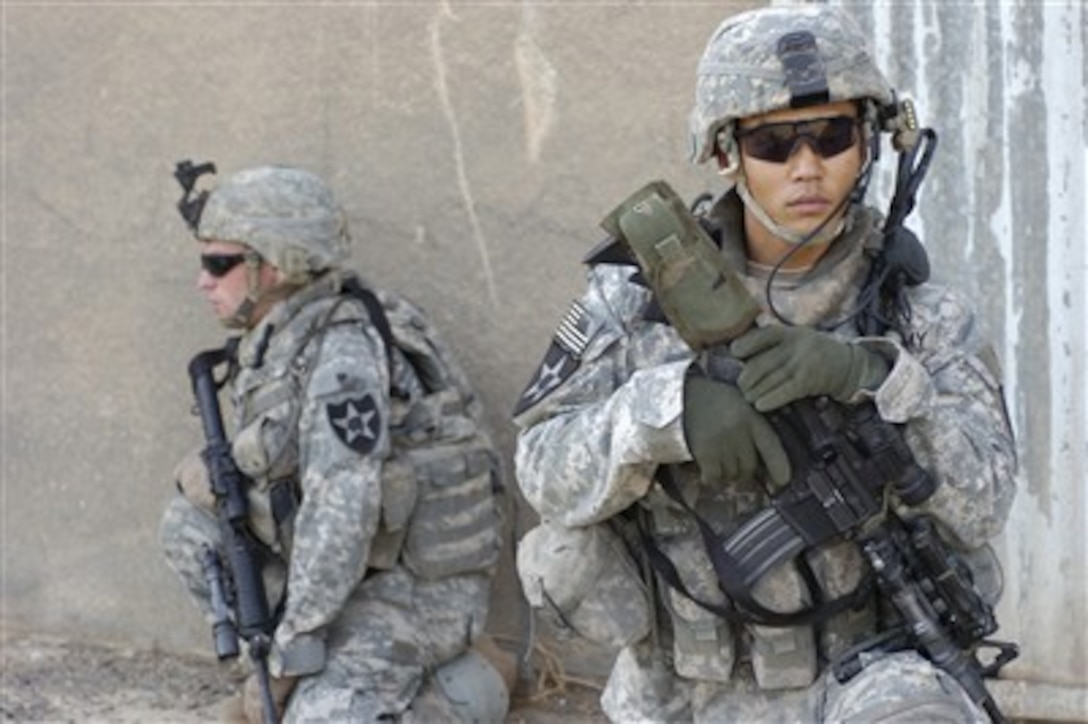 U.S. Army Sgt. Kims Chon (right), team leader with 2nd Platoon, Charlie Battery, 2nd Battalion, 12th Field Artillery Regiment out of Fort Lewis, Wash., and another soldier guard the entrance to a building during an operation in Qudas, Iraq, on Sept. 15, 2007.  