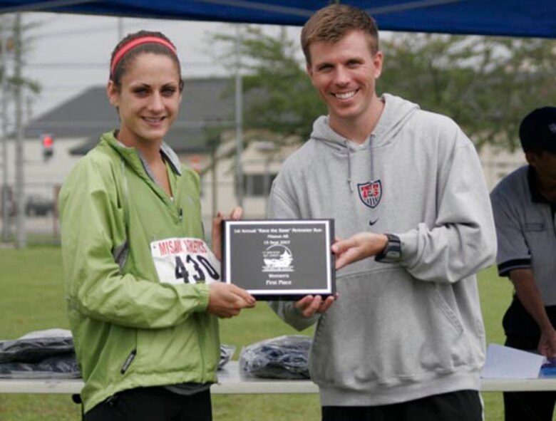 MISAWA AIR BASE, Japan -- Jason Vandenberg (right), 35th Services Squadron fitness director, presents Nicole Sedgwick (left) with a plaque after the first annual "Race the Base" perimeter run here Sept. 15. Ms. Sedgwick was the top female finisher with a 8.5-mile time of 107.07. Charity Lively was the second female finisher with a time of 107.53. Reiko Endo placed third in the female finishers with a time of 113.03. (U.S. Air Force photo) 