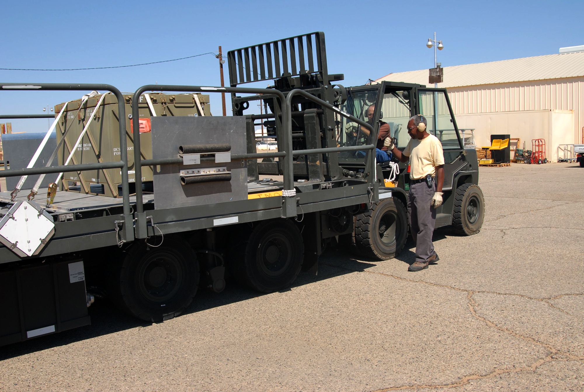Calvin Johnson, Traffic Management Office work leader, assists Andy Spikowski, TMO freight and packing technician, as they utilize a fork lift to load a container on to a transport rig. The transportation division also maintains all special purpose heavy equipment such as loading rigs and fire engines. (Photo by Airman 1st Class Mike Young)