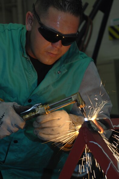 DYESS AIR FORCE BASE, Texas - Senior Airman Troy Wesley, a Metal Technologist, from the 7th Equipment Maintenance Squadron uses a torch to cut down an old metal stand for scrap metal September 18. The Metal Technology shop works on all equipment from mechanics stands to wire welding. (U.S. Air Force photo by Airman 1st Class Jennifer Romig)