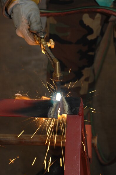 DYESS AIR FORCE BASE, Texas - Senior Airman Troy Wesley, a Metal Technologist, from the 7th Equipment Maintenance Squadron uses a torch to cut down an old metal stand for scrap metal September 18. The Metal Technology shop works on all equipment from mechanics stands to wire welding. (U.S. Air Force photo by Airman 1st Class Jennifer Romig)