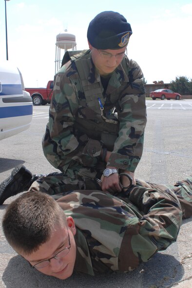 DYESS AIR FORCE BASE, Texas - Airman 1st Class Brooks Reierson from the 7th Security Forces Squadron handcuffs Airman 1st Class Micheal Breaux from the 7th Public Affairs as a part of Security Forces Training September 18. The Security Forces Airmen are train for possible situations. (U.S. Air Force photo by Airman 1st Class Jennifer Romig)
