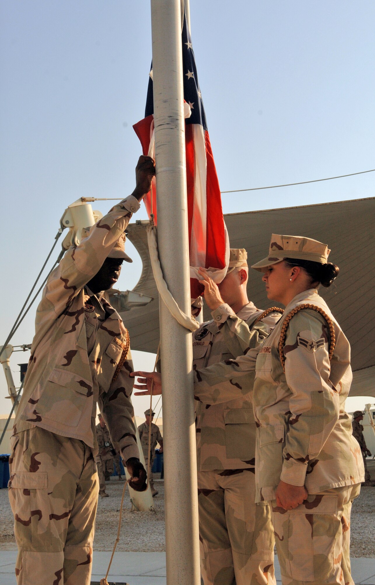 SOUTHWEST ASIA -- Airman 1st Class Miguel Leon (left), Staff Sgt. Christopher McDonald (middle) and Airman 1st Class Evon Hebner (right), 379th Air Expeditionary Wing Honor Guard raise the colors in a reveille ceremony here Tuesday in honor of the Air Force 60th Anniversary. The 379th AEW began a week long celebration beginning Sept. 12 that included fitness related events and specials at Army and Air Force Exchange concessionaires. (U.S. Air Force photo/Master Sgt. Greg Kunkle)