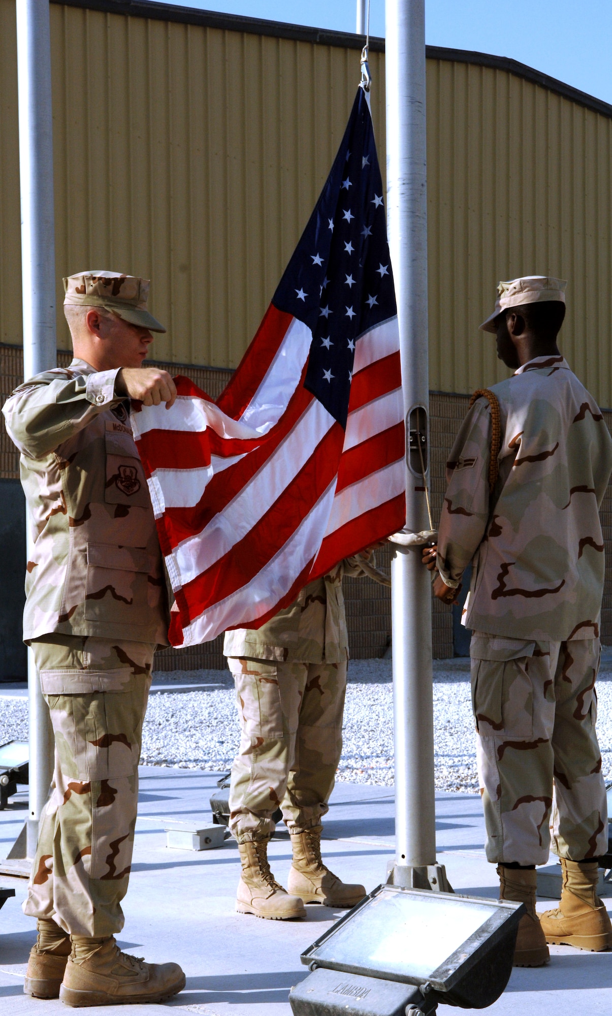 SOUTHWEST ASIA -- Staff Sgt. Christopher McDonald (left), Airman 1st Class Evon Hebner (behind flag) and Airman 1st Class Miguel Leon (right), 379th Air Expeditionary Wing Honor Guard raise the colors in a reveille ceremony here Tuesday in honor of the Air Force 60th Anniversary. The 379th AEW began a week long celebration beginning Sept. 12 that included fitness related events and specials at Army and Air Force Exchange concessionaires. (U.S. Air Force photo/Master Sgt. Greg Kunkle)