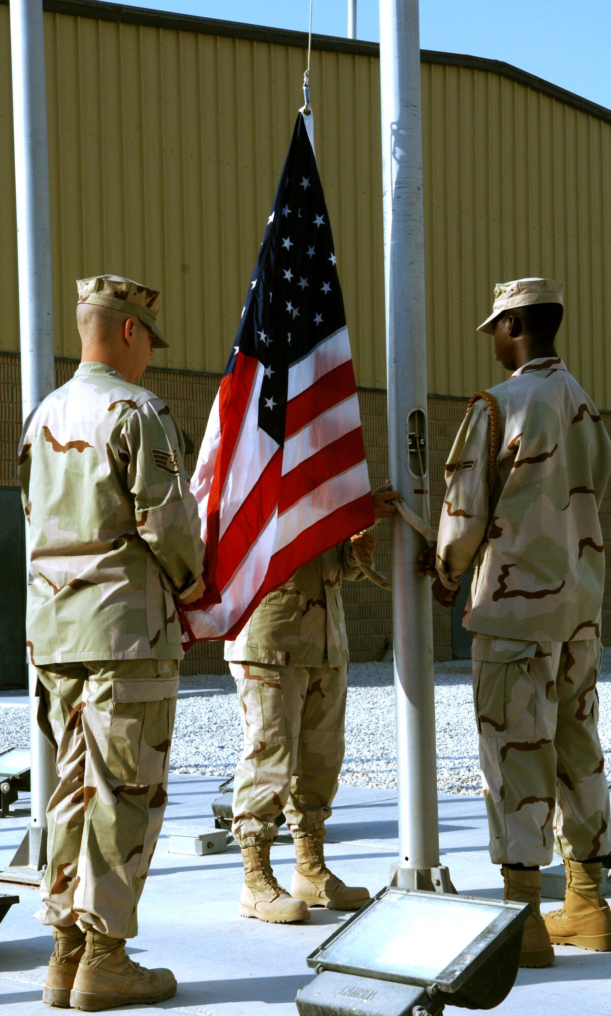 SOUTHWEST ASIA -- Staff Sgt. Christopher McDonald (left), Airman 1st Class Evon Hebner (behind flag) and Airman 1st Class Miguel Leon (right), 379th Air Expeditionary Wing Honor Guard raise the colors in a reveille ceremony here Tuesday in honor of the Air Force 60th Anniversary. The 379th AEW began a week long celebration beginning Sept. 12 that included fitness related events and specials at Army and Air Force Exchange concessionaires. (U.S. Air Force photo/Master Sgt. Greg Kunkle)