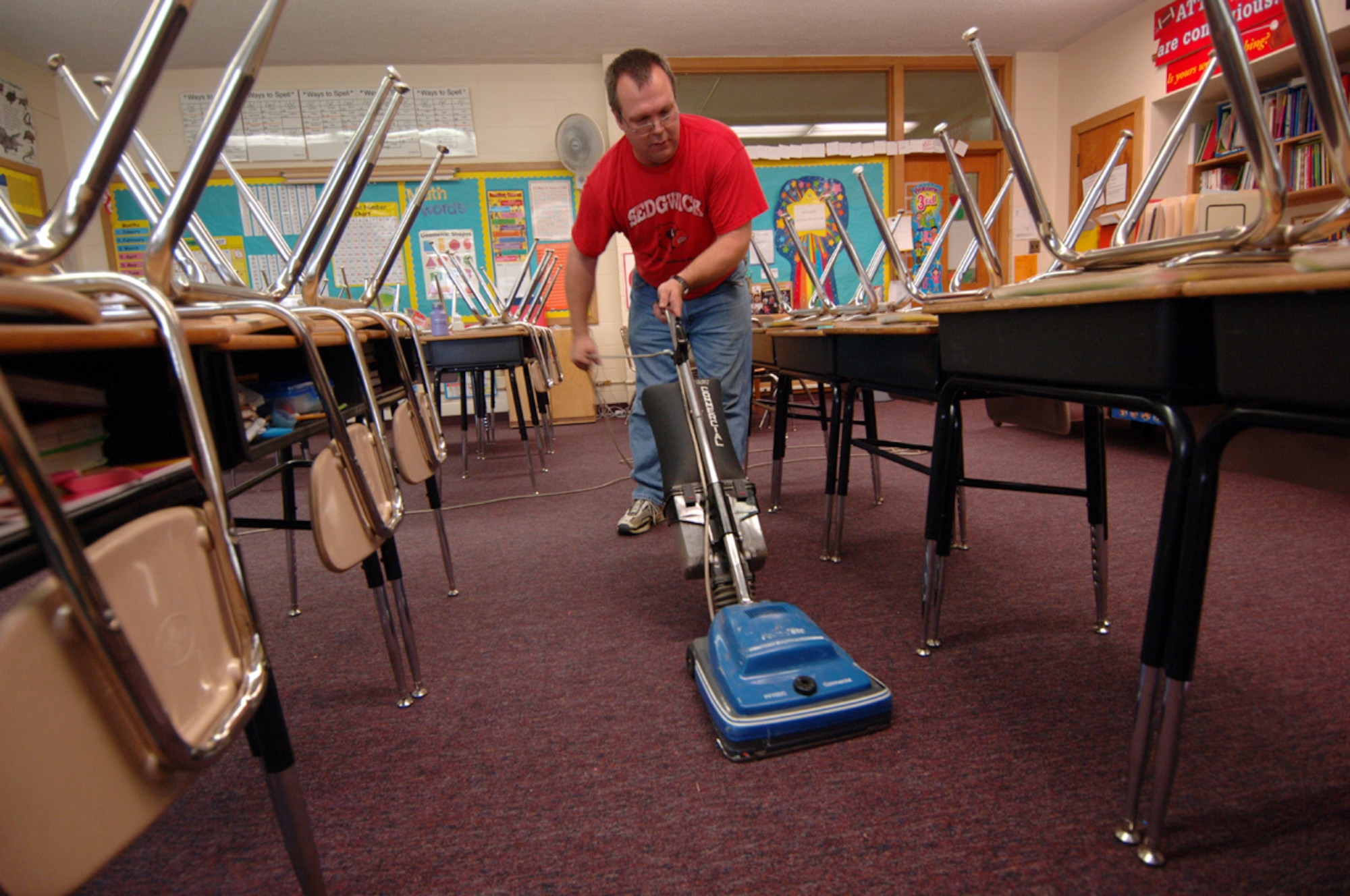 Shelby vacuums a classroom at an elementary school a few blocks from his home. His new job as a janitor involves harder work than the job he was not allowed to return to because of his injury, he said. (Air Force Photo/Tech. Sgt. Jason Schaap)