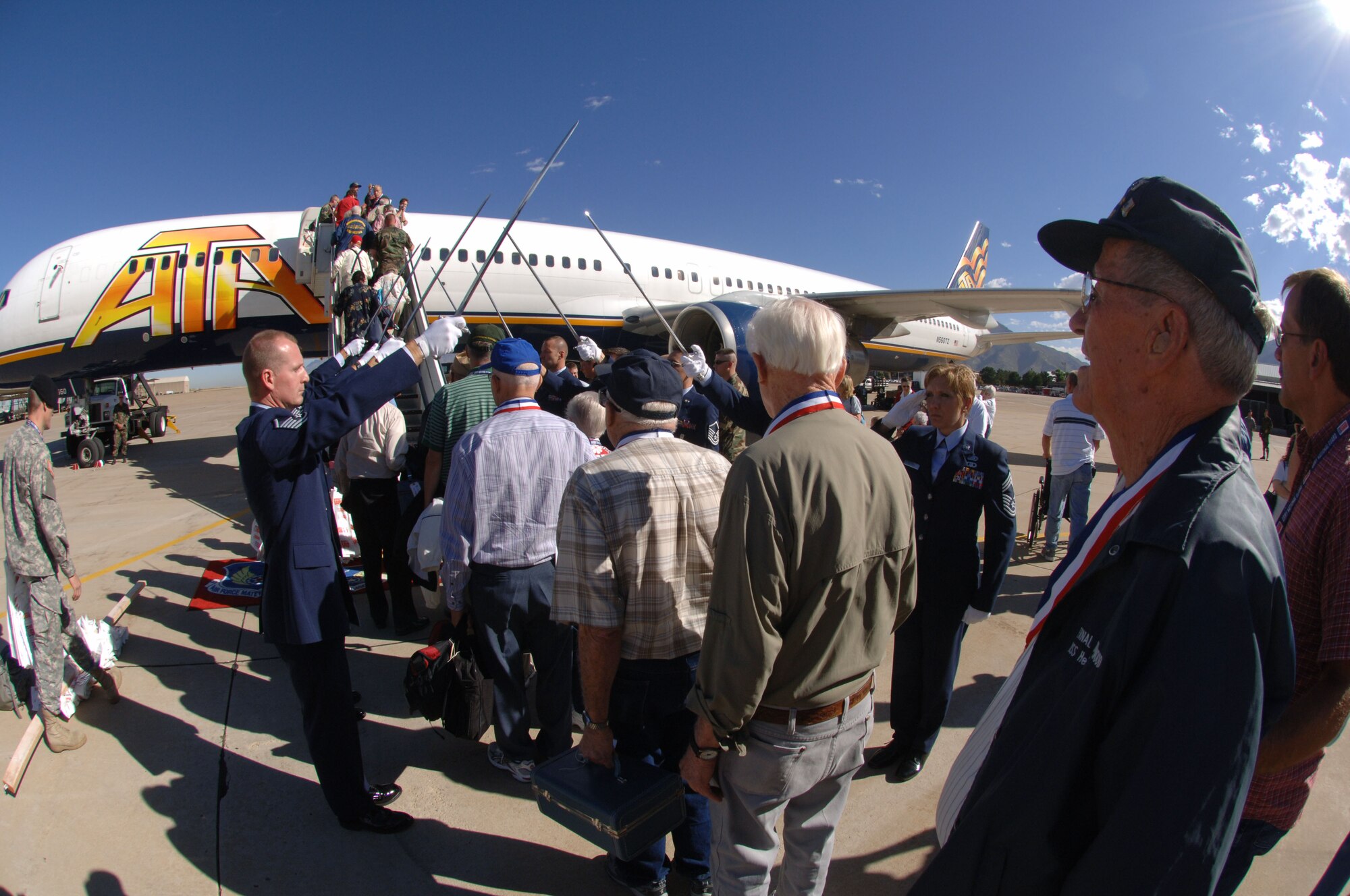 WWII veterans board the aircraft under a saber arch presented by the Hill Air Force Base honor guard. 
