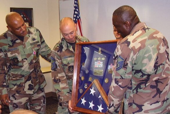 SEYMOUR JOHNSON AIR FORCE BASE, N.C. -- Senior Master Sgt. Jeff Williams (center) and Master Sgt. Pascal Tucker (right) present Senior Master Sgt. Ronald McKenzie with a shadow box during his recent retirement from the 916th Security Forces Squadron. All three were original members when the squadron first started nearly 20 years ago.