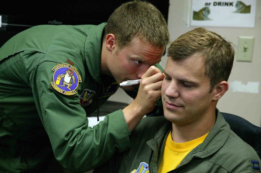 SHAW AIR FORCE BASE, S.C. -- Second Lt. Chris Reichlen (left), 20th Aerospace Medicine Squadron aerospace physiologist, inserts a tube into the ear of Capt. Joe Biedenbach, 79th Fighter Squadron F-16CJ pilot, to make an inner-ear mold for the Attenuating Custom Communications Earpiece System Sept. 14. The ACCES device will significantly reduce surrounding ambient noise that pilots hear in the cockpit and increase the efficiency of radio communications. (U.S. Air Force photo/Senior Airman John Gordinier)