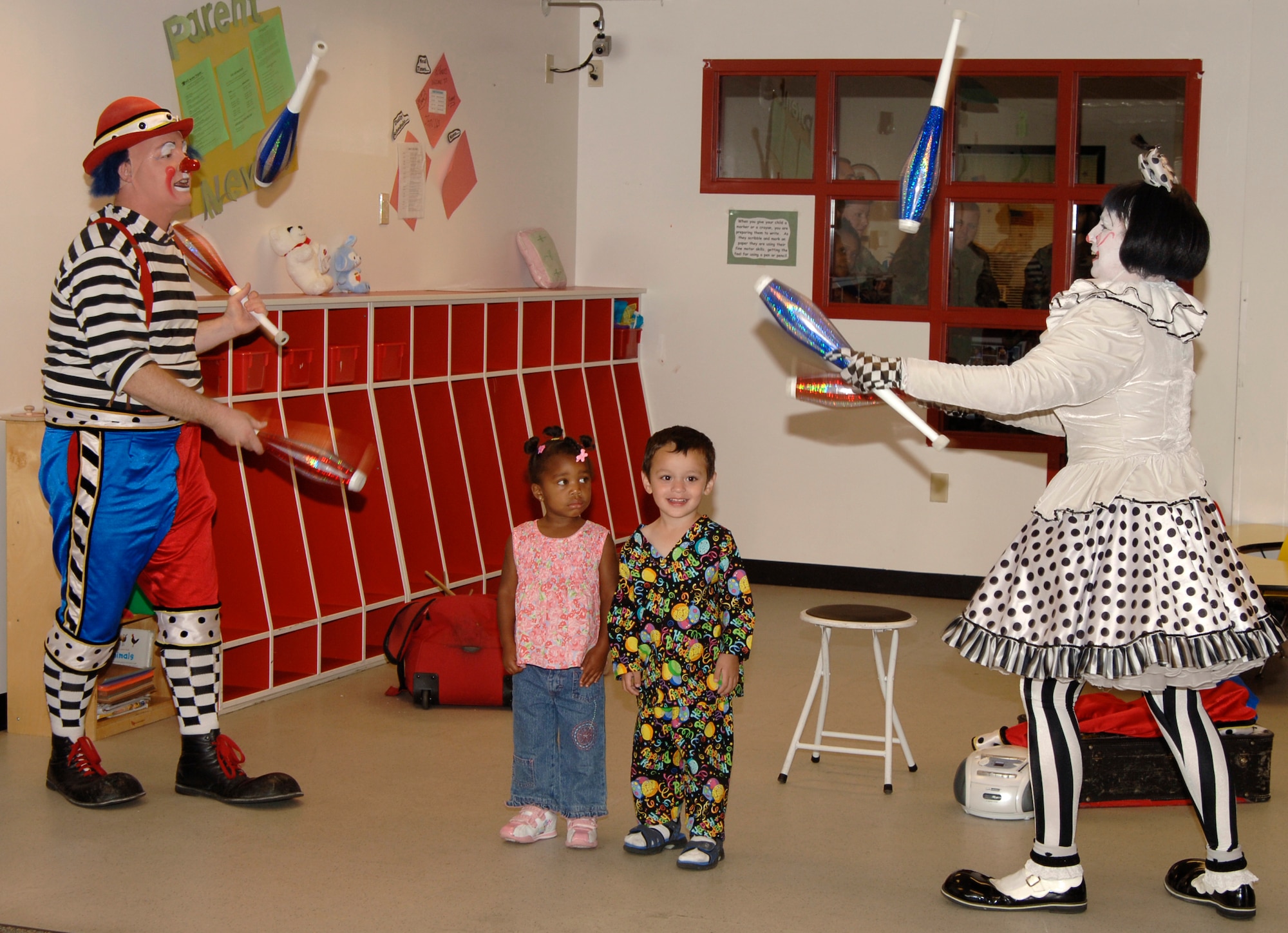 MCCONNELL AIR FORCE BASE, Kan. – Cherie and Dave Gregg, Barnum and Bailey Circus Clowns, juggle pins around 3-year-olds Fantasia Singleton, and Peter Hall, children of Team McConnell members at the Child Development Center, Sept. 14.  (photo by Airman 1st Class Laura Suttles) 