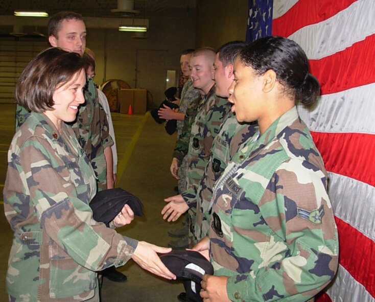 MINOT AIR FORCE BASE, N.D. -- Maj. Patricia Traynor, 5th Bomb Wing Public Affairs acting chief, greets Airmen from the 5th Communications Squadron with a smile and a new 5th Bomb Wing hat during a merger ceremony here Sept. 17. The multimedia section of the 5th CS merged with the 5th BW/PA office during the ceremony. (U.S. Air Force photo by 1st Lt. Sarah Davenport)