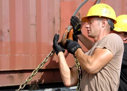 Airman 1st Class Jason Golden, 437th Aerial Port Squadron air transportation specialist and cargo processor, attaches a chain to a crane cable to remove a 40-foot container from a flatbed truck Sept. 13 at the aerial port. (U.S. Air Force photo/Airman 1st Class Katie Gieratz)