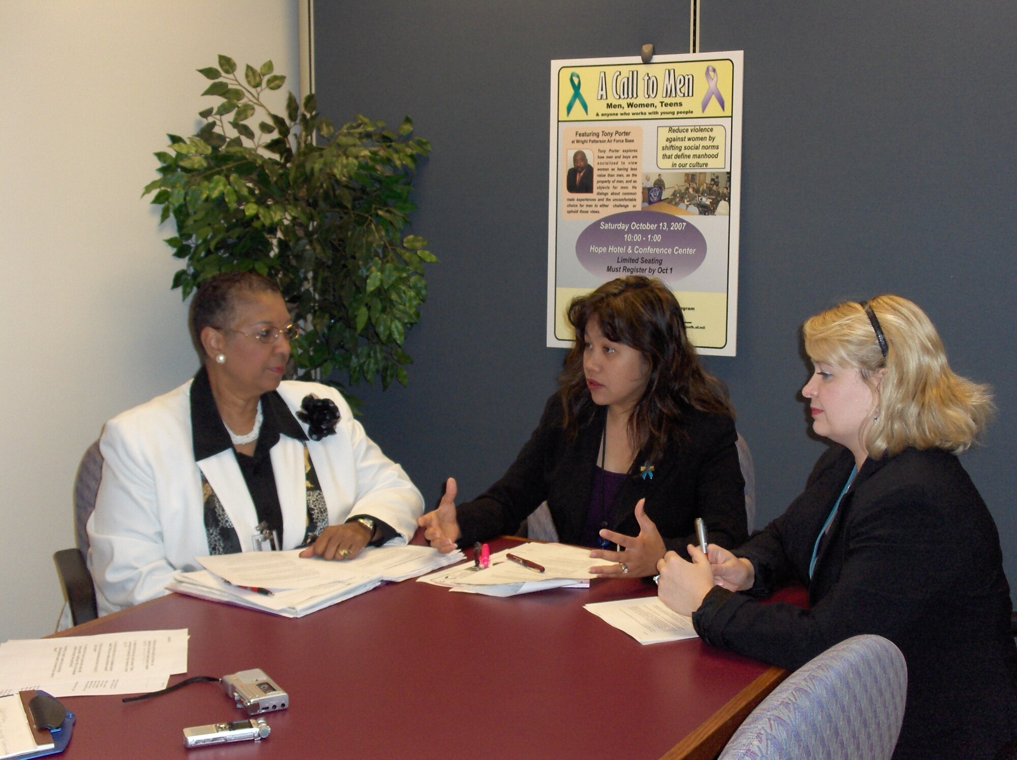 From left, Derry McCurdy, program manager, Federal Womens Program; Simone Koram, sexual assault response coordinator; and Carmen Schott, family advocacy program outreach manager, discuss the upcoming workshop “A Call to Men,” featuring motivational speaker Tony Porter, which will address the problem of domestic violence. Skywrighter photo by Christy Webb.

