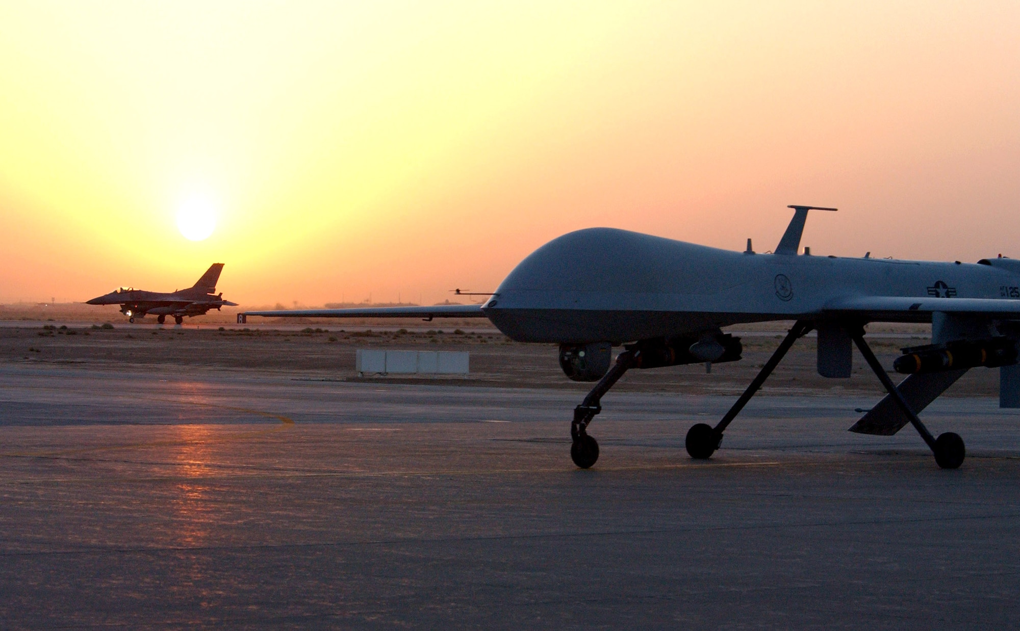 An MQ-1 Predator unmanned aerial vehicle and F-16 Fighting Falcon return from an Operation Iraqi Freedom combat mission. Both aircraft provide intelligence, search and reconnaissance gathering features, as well as munitions capability to support ground troops and base defense. (U.S. Air Force photo/1st Lt. Shannon Collins)              