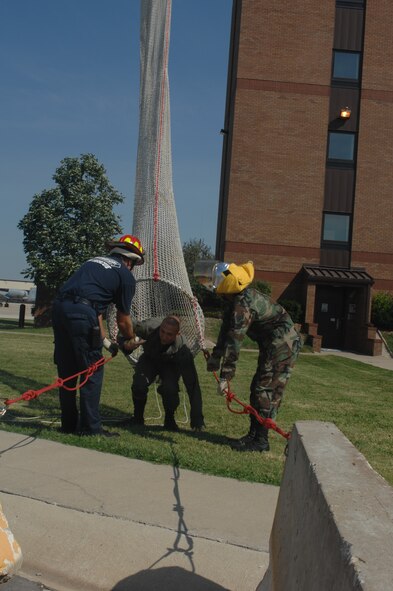 WHITEMAN AIR FORCE BASE, Mo. -- Mark Kinsey and Airman 1st Class Rocky Vazquez, 509th Civil Engineer Squadron Fire Department, help Airman 1st Class Robert Ervin, 509th Operations Support Squadron, exit the drop shoot during annual evacuation training Sept. 18. (U.S. Air Force photo/Tech. Sgt. Samuel A. Park) 